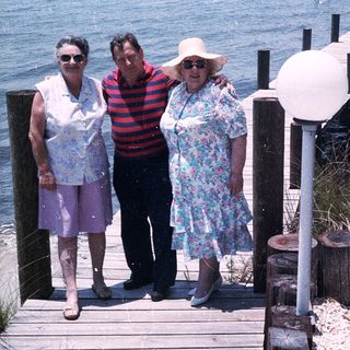 Three people posing on a seaside boardwalk.