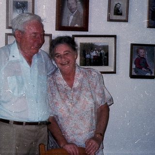 Happy elderly couple posing indoors with family photos.