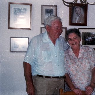 Happy elderly couple posing indoors with family photos.