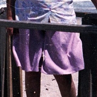 Two elderly people standing on beach stairs by ocean.