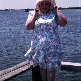 Woman smiling by water, holding fishing net.