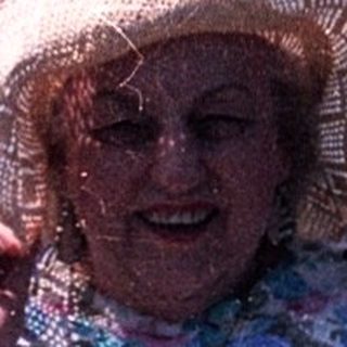 Woman smiling by water, holding fishing net.