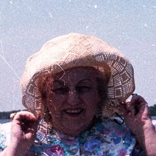 Woman smiling by water, holding fishing net.