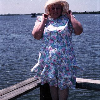Woman smiling by water, holding fishing net.