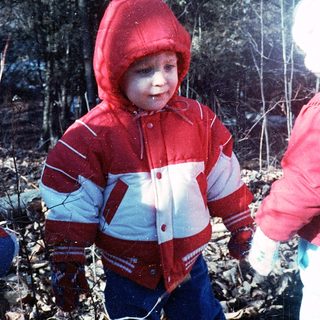 Young child wearing red and white winter jacket outdoors.