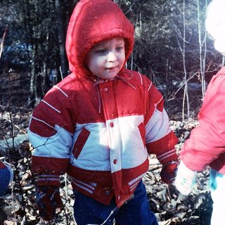 Young child wearing red and white winter jacket outdoors.