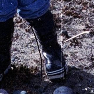 Young child wearing winter gear playing outdoors.