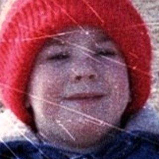 Young child wearing winter gear playing outdoors.