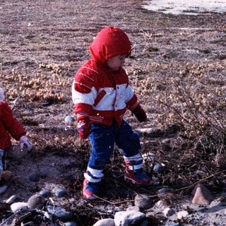 Three children playing outdoors on rocky ground.