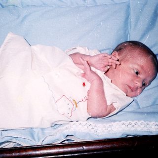 Newborn baby wrapped in white blanket.