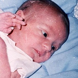 Newborn baby wrapped in white blanket.