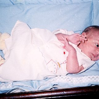 Newborn baby wrapped in white blanket.