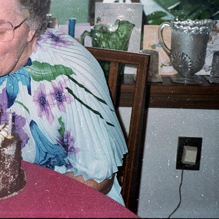 Woman blowing out birthday cake candles indoors.