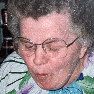 Woman blowing out birthday cake candles indoors.