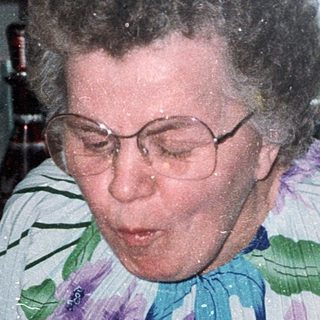 Woman blowing out birthday cake candles indoors.