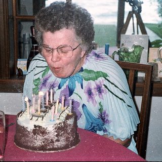 Woman blowing out birthday cake candles indoors.