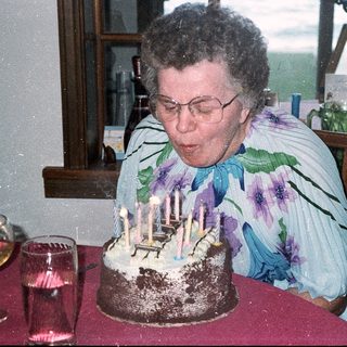 Woman blowing out birthday cake candles indoors.