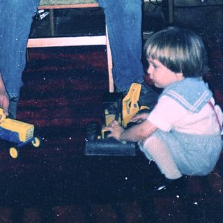 Man helping child play with toy car.