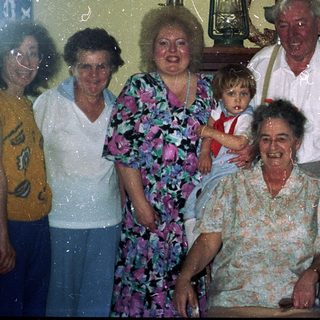 Family group photo with elderly and young relatives indoors.