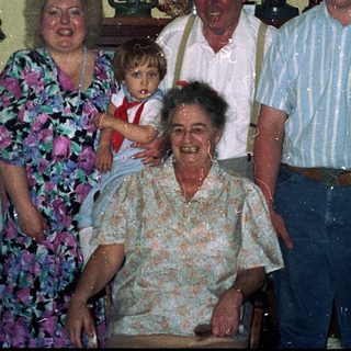 Family group photo with elderly and young relatives indoors.