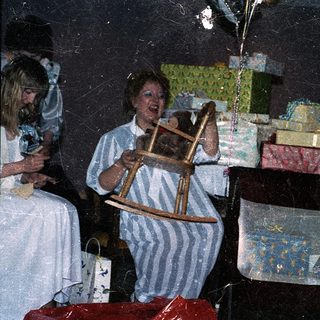 Woman playing rocking horse with child near wrapped gifts.