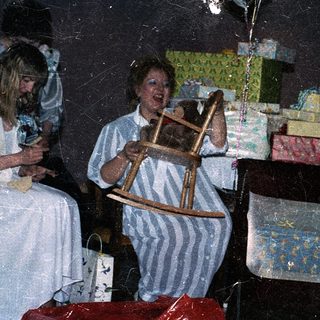 Woman playing rocking horse with child near wrapped gifts.