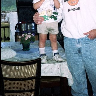 Man and young child posing indoors near kitchen.