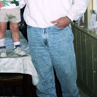 Man and young child posing indoors near kitchen.