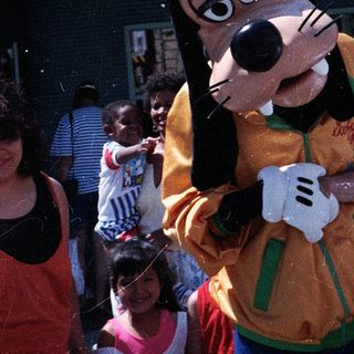 Costumed Goofy interacting with crowd outdoors.