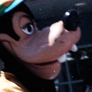 Costumed mascot interacting with crowd outdoors.