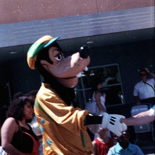 Costumed mascot interacting with crowd outdoors.