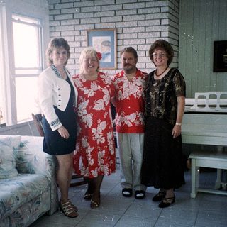 Four people posing indoors in casual summer attire.