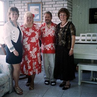 Four people posing indoors in casual summer attire.