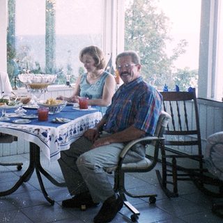Family enjoying meal indoors near large windows.