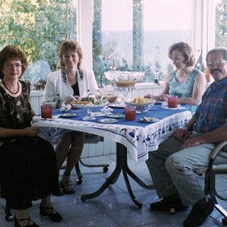 Family enjoying meal indoors near large windows.