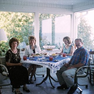 Family enjoying meal indoors near large windows.