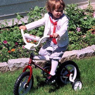 Young child riding small bicycle near garden.