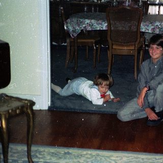 Two children playing on wooden floor indoors.