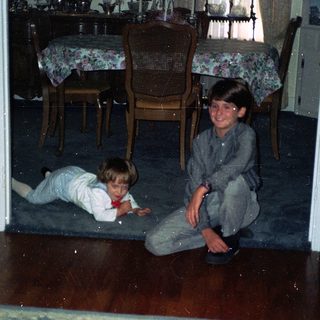 Two children playing on wooden floor indoors.