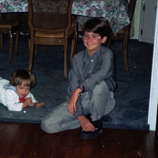 Two children playing on wooden floor indoors.