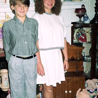 Two children posing indoors in 1980s-style clothing.