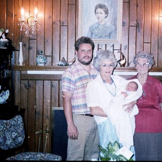 Family portrait with baby, three adults, rustic interior.