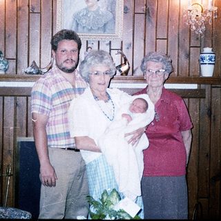 Family portrait with baby, three adults, rustic interior.