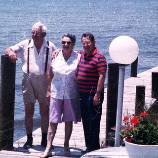 Three adults posing by a waterfront dock.