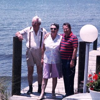 Three adults posing by a waterfront dock.