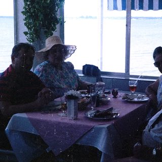 Group of four people dining together indoors near water.