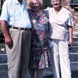 Three elderly individuals posing together outdoors.