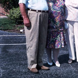Three elderly individuals posing together outdoors.