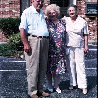 Three elderly individuals posing together outdoors.