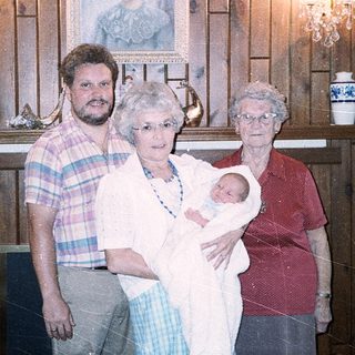 Family posing with newborn in vintage home setting.